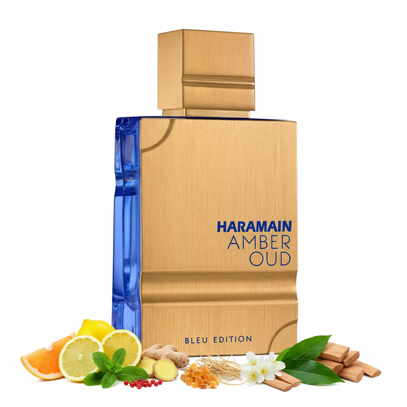 Frasco de perfume Amber Oud Bleu Edition de Al Haramain EDP, botella rectangular con paneles frontales en oro cepillado satén y laterales en vidrio azul real transparente, esquinas cóncavas curvas, texto azul marino HARAMAIN AMBER OUD BLEU EDITION en panel dorado, cuello escalonado dorado y gran tapón cuadrado dorado cepillado, sobre fondo blanco, rodeado de toronja, limón, menta, pimienta rosa, jengibre, vetiver, jazmín, incienso, sándalo, pachulí y cedro.