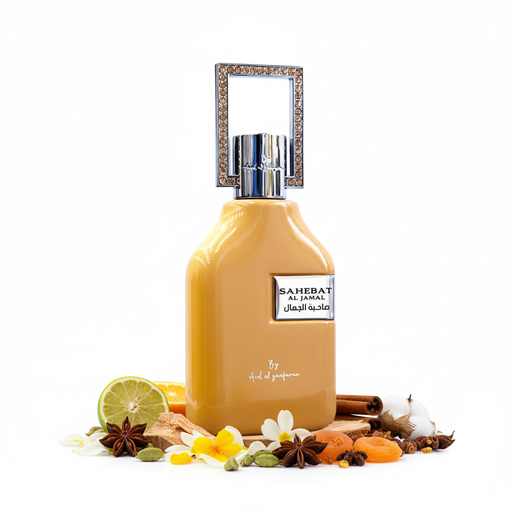 Frasco de perfume Sahebat Al Jamal de Ard Al Zaafaran EDP, botella cuadrada redondeada amarillo-dorado brillante con hombros achaflanados, placa plateada con texto SAHEBAT AL JAMAL y caligrafía árabe صاحبة الجمال, script blanco By Ard al zaafaran, cuello cilíndrico plateado y gran marco rectangular abierto con cristales brillantes incrustados, sobre fondo blanco, rodeado de cítricos, bergamota, flores, especias, frutas, maderas, ámbar y almizcle.