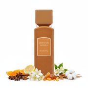 Frasco de perfume Desert de Sahara de Riiffs Extrait de Parfum 100ml, botella rectangular con textura granulada arena marrón caramelo, hombros achaflanados, etiqueta arco ámbar con texto dorado DESERT DE SAHARA y RiIFFS, tapón cuadrado cobre-oro rosa, sobre fondo blanco, rodeado de cítricos, especias, jazmín, flor de azahar, ámbar, cedro y almizcle.