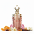 Frasco Papillon des Vents de Paris Corner EDP, botella jarrón rosa-dorado cobrizo con gotas en relieve, mariposa dorada filigrana en el cuerpo superior, texto Papillon des Vents Paris Corner, tapa corona dorada con remate diamante, rodeado de mandarina, peonía, azahar, orquídea vainilla, ambroxan, vainilla y tonka.