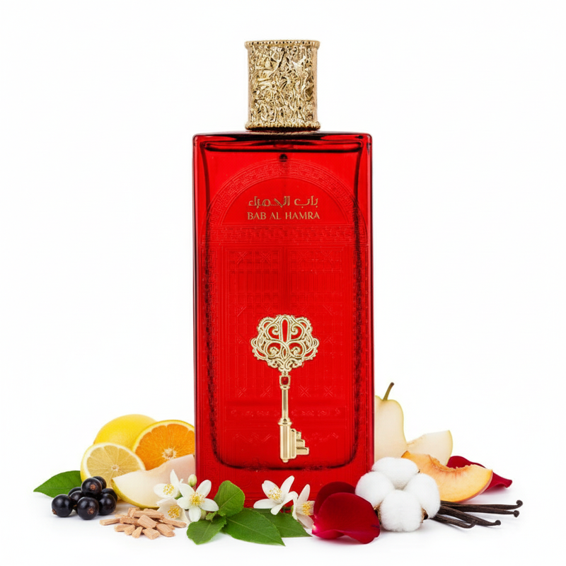 Frasco Bab Al Hamra EDP, botella rectangular rubí rojo con arco moro y caligrafía árabe BAB AL HAMRA grabados en el vidrio, llave esqueleto dorada filigrana ornamental en el centro, tapa cilíndrica dorada con textura martillada, sobre fondo blanco, rodeado de cítricos, grosella negra, pera, melocotón, jazmín, azahar, rosa, pachulí, sándalo, almizcle blanco y vainilla.