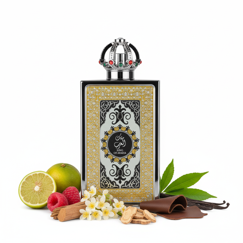 Frasco de perfume King of Arabia de Lattafa EDP 100ml, botella rectangular con marco plateado floral, banda dorada ornamentada, panel blanco con arabescos negros y medalón circular con caligrafïa árabe KING OF ARABIA, tapón corona real plateada con gemas rubí rojo y esmeralda verde y banda de diamantes, sobre fondo blanco, rodeado de bergamota, frambuesa, cedro, osmanto, raíz de lirio, cuero, vainilla y pachulí.