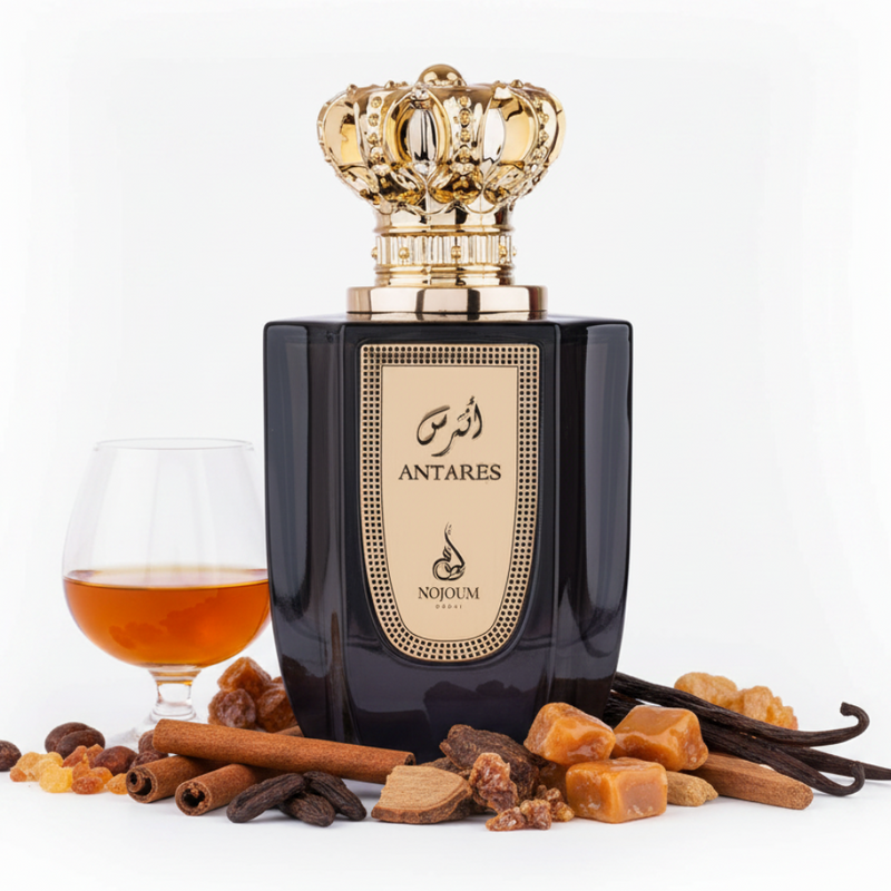 Frasco Antares de Nojoum Dubai EDP, botella rectangular negra espresso brillante con placa dorada grande y borde punteado, caligrafía árabe أنتارس y texto ANTARES NOJOUM DUBAI en oscuro, cuello dorado acanalado, tapa corona real ornamentada en oro brillante, rodeado de coñac, ámbar, canela, tonka, roble, praliné, vainilla y sándalo.