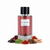Frasco de perfume L'Oudh de Maison Alhambra EDP 100ml, botella cilíndrica de vidrio transparente con líquido rosa-rojo, etiqueta blanca minimalista y tapón negro acanalado, sobre fondo blanco, rodeado de ládano, pétalos de rosa, pachulí, azafrán, madera de oud, sándalo y cedro.